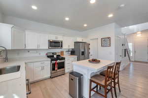 Kitchen featuring stainless steel appliances, a kitchen island, sink, light hardwood / wood-style floors, and white cabinetry