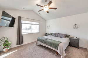 Carpeted bedroom with ceiling fan and lofted ceiling