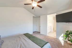 Bedroom featuring ceiling fan, light colored carpet, lofted ceiling, and connected bathroom