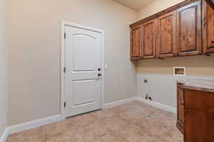 Washroom featuring hookup for an electric dryer, light tile patterned flooring, cabinets, and hookup for a washing machine