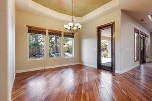 Interior space with dark wood-type flooring, a tray ceiling, and a notable chandelier