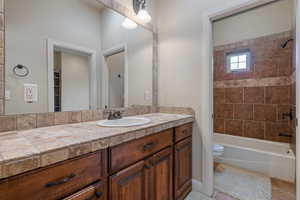 Full bathroom with vanity, tiled shower / bath combo, and toilet