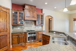 Kitchen with decorative light fixtures, sink, light stone countertops, and stainless steel appliances