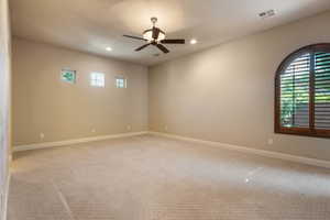 Empty room featuring ceiling fan and light carpet