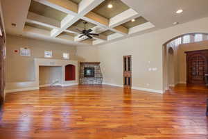 Unfurnished living room featuring ceiling fan, beamed ceiling, a high ceiling, and coffered ceiling