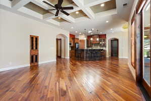 Unfurnished living room with beam ceiling, dark wood-type flooring, ceiling fan, and coffered ceiling