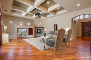 Living room featuring ceiling fan, beamed ceiling, a high ceiling, and coffered ceiling