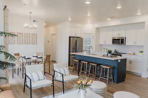 Pics are of model home.Kitchen with white cabinets, sink, an island with sink, appliances with stainless steel finishes, and a chandelier