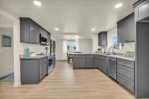 Kitchen with gray cabinets, sink, plenty of natural light, and appliances with stainless steel finishes