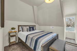 Carpeted bedroom featuring lofted ceiling