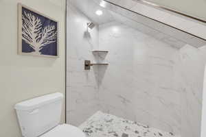 Bathroom featuring a tile shower and toilet