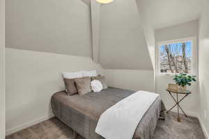 Carpeted bedroom featuring vaulted ceiling with beams