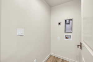 Clothes washing area featuring hookup for an electric dryer, hookup for a washing machine, and light wood-type flooring