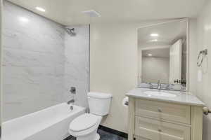 Full bathroom with toilet, vanity, and tiled shower / bath combo