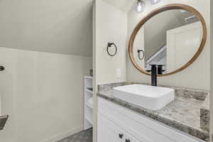 Bathroom featuring vanity and vaulted ceiling