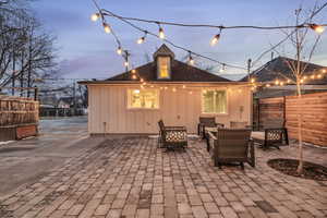 Back house at dusk featuring an outdoor hangout area and a patio