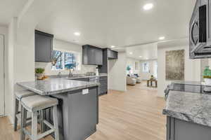 Kitchen with a kitchen breakfast bar, gray cabinets, light hardwood / wood-style flooring, and sink