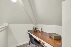 Carpeted office with vaulted ceiling with beams