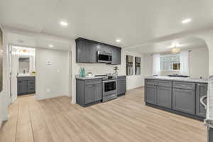 Kitchen featuring gray cabinets, light stone countertops, light hardwood / wood-style floors, and appliances with stainless steel finishes