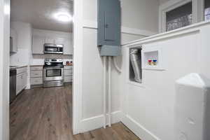 Kitchen featuring a textured ceiling, electric panel, stainless steel appliances, and dark hardwood / wood-style flooring