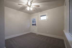 Spare room with a textured ceiling, dark carpet, and ceiling fan