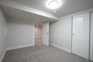 Basement featuring light colored carpet and a textured ceiling