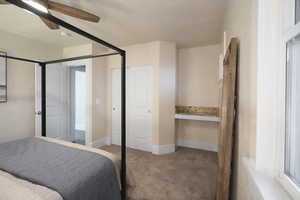 Bedroom with connected bathroom, ceiling fan, and light colored carpet