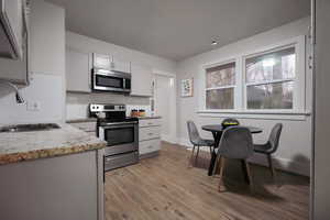 Kitchen featuring sink, light hardwood / wood-style flooring, tasteful backsplash, light stone counters, and stainless steel appliances