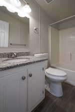 Full bathroom with vanity, a textured ceiling, bathing tub / shower combination, hardwood / wood-style flooring, and toilet