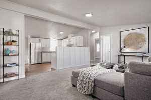 Living room featuring carpet, a textured ceiling, and lofted ceiling