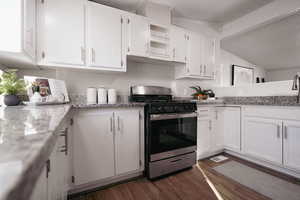 Kitchen featuring gas range, white cabinetry, light stone countertops, and dark hardwood / wood-style floors