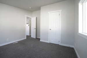 Unfurnished bedroom with dark carpet and a closet