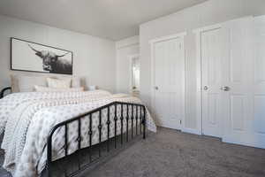 Bedroom with dark colored carpet and multiple closets