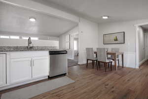 Kitchen featuring dishwasher, dark wood-type flooring, white cabinets, sink, and vaulted ceiling