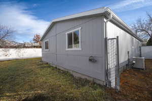 View of side of home with a yard and central AC