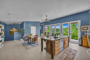 Kitchen with french doors, sink, dishwasher, hanging light fixtures, and an island with sink