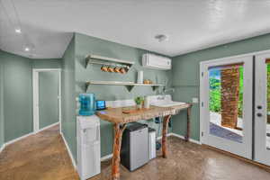 Kitchen with refrigerator, a textured ceiling, concrete floors, and a wall mounted AC