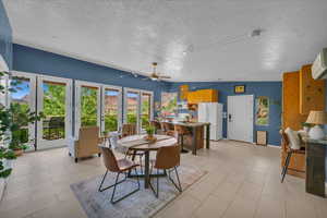 Dining space with ceiling fan, an AC wall unit, a textured ceiling, and french doors