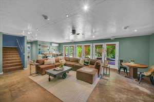 Living room with plenty of natural light, a textured ceiling, and french doors