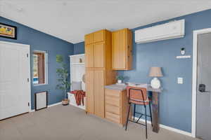 Kitchen featuring a kitchen breakfast bar, light brown cabinetry, a wall unit AC, and vaulted ceiling