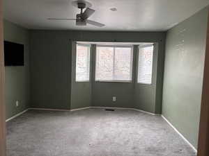 Carpeted main bedroom featuring ceiling fan