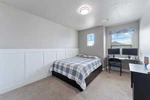 Bedroom featuring light carpet and a textured ceiling