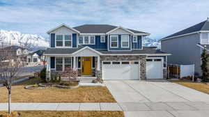 View of front of home with a mountain view, a garage, and a front lawn