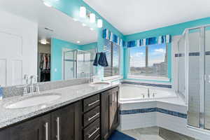 Bathroom featuring vanity, tile patterned flooring, and plus walk in shower