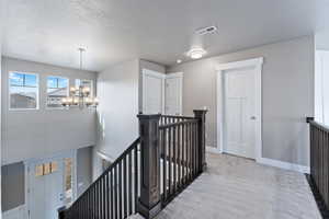 Corridor featuring carpet flooring, a notable chandelier, and a textured ceiling