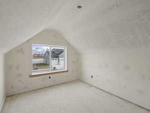 Additional living space with a textured ceiling and lofted ceiling