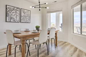 Dining space with light hardwood / wood-style floors and an inviting chandelier