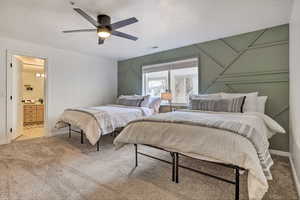 Carpeted bedroom featuring a textured ceiling, ensuite bathroom, and ceiling fan