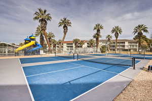 View of tennis court with basketball hoop and a playground