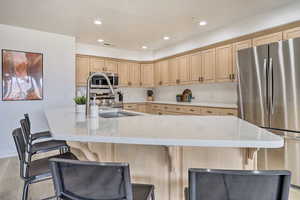 Kitchen featuring appliances with stainless steel finishes, light brown cabinets, a spacious island, and a breakfast bar area